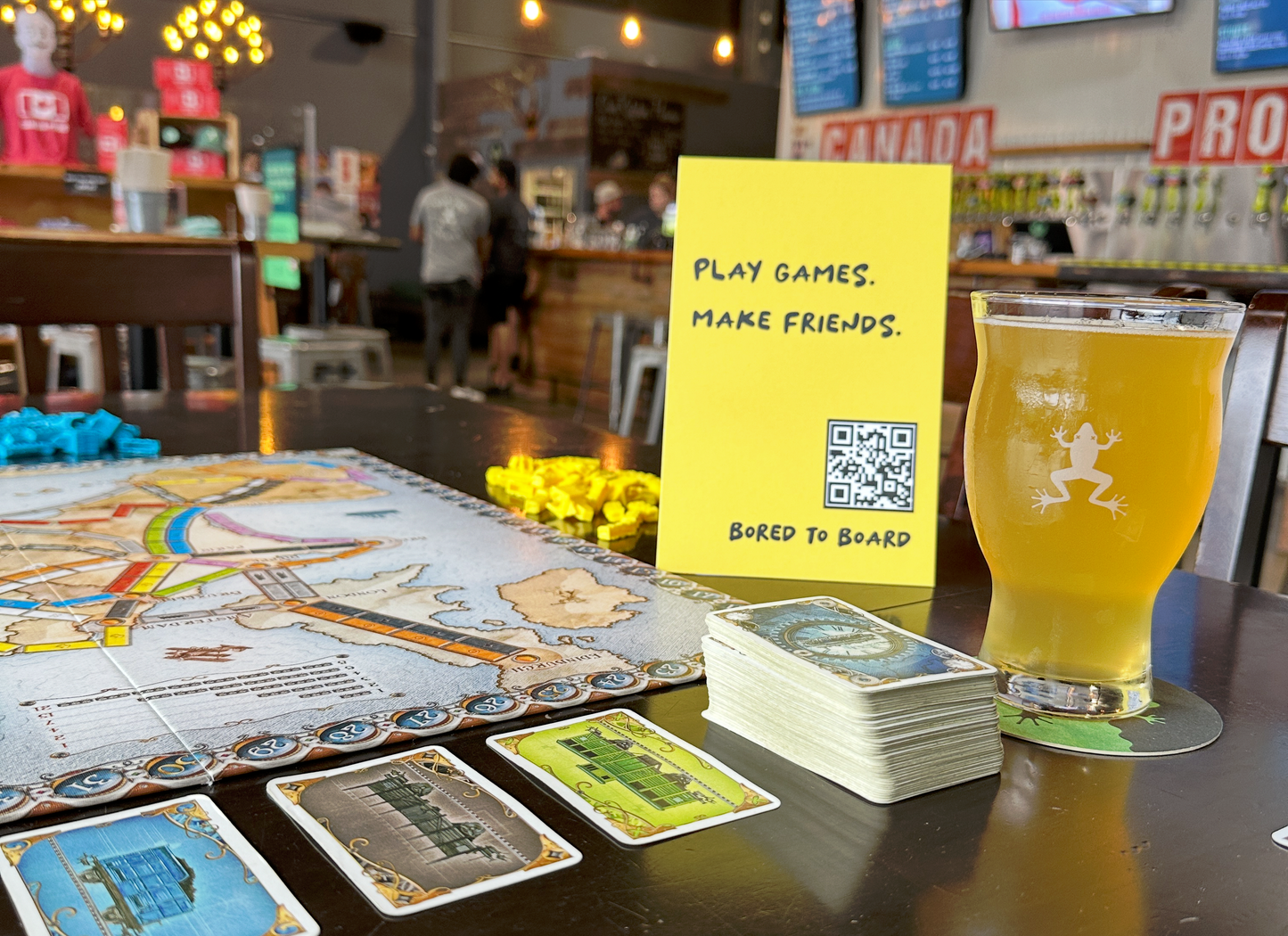 Board game setup with a glass of beer and a sign encouraging play and friendship.